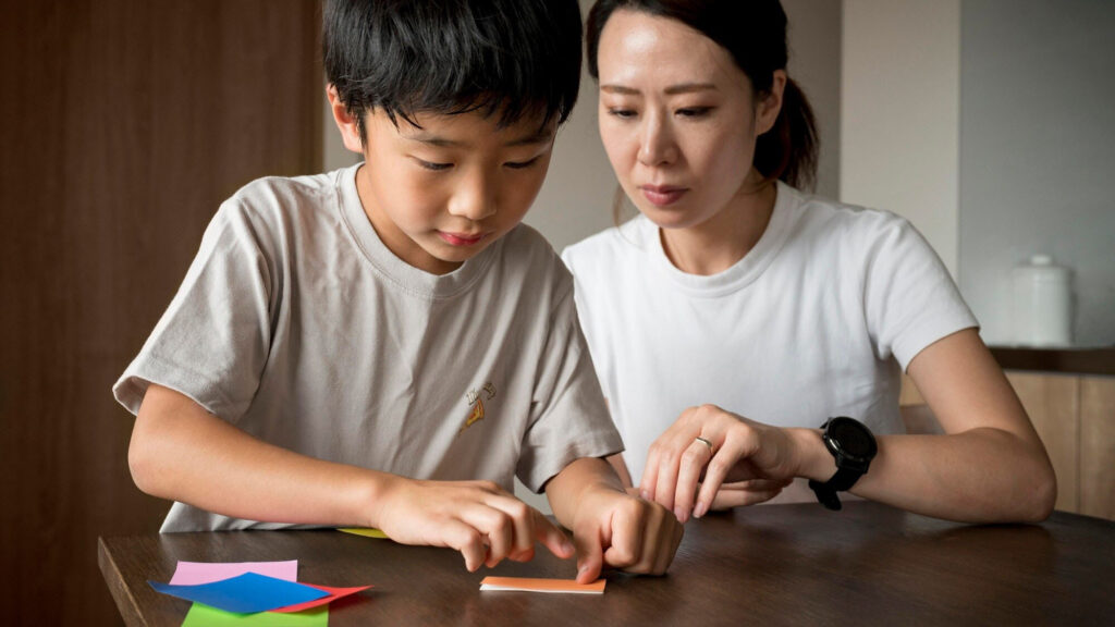 Mother helping son with a paper activity, using speech-language pathology techniques